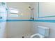 Bathroom shower with white and blue tile, toilet and window at 12311 Oakwood Dr, Hudson, FL 34669