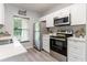 Bright kitchen features stainless steel appliances, white cabinets and countertops with view at 1250 Charlesworth Dr, Wesley Chapel, FL 33543