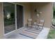 Outdoor patio features sliding glass doors, two chairs and small table, and striped rug at 1250 Charlesworth Dr, Wesley Chapel, FL 33543