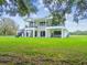 Expansive two-story home with a modern white brick exterior, balconies, outdoor seating, and a sprawling green lawn at 13711 Lussier Ln, Spring Hill, FL 34610