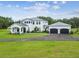 Stunning two-story white home with metal roof, manicured lawn, and three car garage at 13711 Lussier Ln, Spring Hill, FL 34610