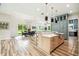 Bright open-concept kitchen and dining area featuring a large island with seating, stainless steel appliances, and modern lighting at 13711 Lussier Ln, Spring Hill, FL 34610