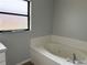 Bright bathroom featuring a soaking tub with white tile surround and frosted window at 13742 14Th St, Dade City, FL 33525