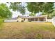 A well-sized backyard with lush green grass, a fence, mature trees, and a covered porch at 1426 Buckner Rd, Valrico, FL 33596