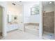 Bright bathroom with large soaking tub, tiled walk-in shower, and vanity with double sinks and white cabinetry at 1426 Buckner Rd, Valrico, FL 33596