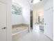 Bright bathroom featuring a soaking tub with tiled surround and a separate glass enclosed shower stall at 1426 Buckner Rd, Valrico, FL 33596