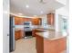 Well-lit kitchen features wood cabinets, stainless appliances, and a breakfast bar overlooking a sliding glass door at 1426 Buckner Rd, Valrico, FL 33596