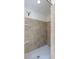 Walk-in shower featuring neutral tile walls and flooring with a shower head and toiletry shelves at 1426 Buckner Rd, Valrico, FL 33596
