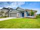 Charming single-story home with a manicured lawn, gray garage door, and blue front door at 16511 66Th E Ln, Parrish, FL 34219
