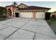 Charming home featuring an arched entryway and a spacious three-car garage with a concrete driveway at 18104 Sweet Jasmine Dr, Tampa, FL 33647