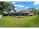 View of the screened-in pool and backyard of this house on a sunny day, featuring a lush lawn and mature trees at 1951 Downing Pl, Palm Harbor, FL 34683