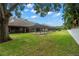 Screened pool enclosure in backyard viewed from grassy lawn with mature trees at 1951 Downing Pl, Palm Harbor, FL 34683