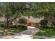 Charming single-story home with a circular driveway framed by mature trees and manicured landscaping at 1951 Downing Pl, Palm Harbor, FL 34683