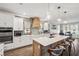 Bright kitchen with white cabinets, quartz countertops, wooden vent hood, stylish backsplash, and an island with seating at 22294 Storybook Cabin Way, Land O Lakes, FL 34637
