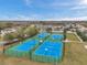 Aerial view of tennis and basketball courts with blue surfaces in a residential community on a sunny day at 22294 Storybook Cabin Way, Land O Lakes, FL 34637