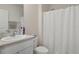 Bright bathroom showcasing a functional vanity, commode, and shower with a white curtain, offering essential amenities at 2449 Moon Shadow Rd, New Port Richey, FL 34655