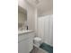 Bright bathroom showcasing a functional vanity, commode, and shower with a white curtain, plus blue floor mat at 2449 Moon Shadow Rd, New Port Richey, FL 34655