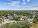 Scenic aerial view showcasing a neighborhood with mature trees, green spaces, and nearby commercial areas at 2667 Aspen Ct, Palm Harbor, FL 34684