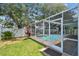 Landscaped backyard featuring a screened-in pool and lush greenery at 2667 Aspen Ct, Palm Harbor, FL 34684