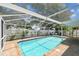Sparkling screened-in pool with brick patio, outdoor furniture, and a grill, perfect for outdoor relaxation at 2667 Aspen Ct, Palm Harbor, FL 34684