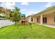 Spacious backyard with a covered patio and a wooden playset for outdoor fun at 2973 Breezy Meadows, Clearwater, FL 33760