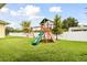 Backyard with lush green grass and a wooden playset with swings and a slide at 2973 Breezy Meadows, Clearwater, FL 33760