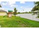 Large backyard with lush lawn, white fence, and wooden playset with slide at 2973 Breezy Meadows, Clearwater, FL 33760