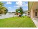 Green lawn with wooden playset, including swings and a slide, next to a white vinyl fence at 2973 Breezy Meadows, Clearwater, FL 33760