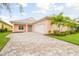 Charming peach-colored home with a paver driveway and well-manicured landscaping at 2973 Breezy Meadows, Clearwater, FL 33760