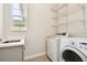 Bright laundry room featuring a sink, modern washer and dryer, and wire shelving at 2973 Breezy Meadows, Clearwater, FL 33760