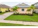 Manicured lawn with fresh landscaping around a peach colored house with gray roof at 2973 Breezy Meadows, Clearwater, FL 33760
