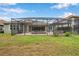 Green backyard features a large, screened-in patio with an outdoor kitchen and plenty of room for entertaining at 3326 Barbour Trl, Odessa, FL 33556