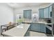 Bright kitchen featuring blue cabinets, stainless appliances, marble countertops, and a modern island and dining area at 3762 Darston St, Palm Harbor, FL 34685