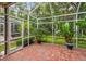 Screened lanai featuring a brick floor, tropical plants, and access to outdoor spaces at 3762 Darston St, Palm Harbor, FL 34685