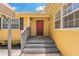 Inviting home entrance with a bright red door and gray wood stairs at 39542 Friends Ave, Zephyrhills, FL 33540