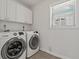 Bright laundry room featuring a newer washer and dryer along with upper cabinets at 39542 Friends Ave, Zephyrhills, FL 33540