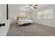 Cozy main bedroom featuring two windows, neutral carpet, ceiling fan, and a wooden bedframe at 39542 Friends Ave, Zephyrhills, FL 33540