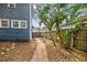 Backyard view of a blue house with tropical plants and foliage along the paved path and wooden fence at 4016 N Seminole Ave, Tampa, FL 33603