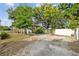 Large backyard with trees, a wooden fence and a white fence enclosing a graveled area and the home at 4016 N Seminole Ave, Tampa, FL 33603