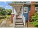 Exterior shot displaying the steps leading to the charming covered front porch with brick and white railing at 4016 N Seminole Ave, Tampa, FL 33603