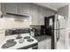 Bright kitchen featuring gray cabinets, a white stove, black refrigerator, and tiled backsplash at 4305 Summersun Dr, New Port Richey, FL 34652