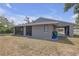 Backyard of gray house featuring a screened-in porch and access to the carport for easy entry and exit at 4623 Wisteria Dr, Zephyrhills, FL 33542