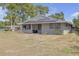 Inviting single-story home with a gray exterior, solar panels and a partially shaded front yard at 4623 Wisteria Dr, Zephyrhills, FL 33542