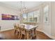 Sunlit dining area with wood floors, rustic table, statement chandelier, and bright windows overlooking lush greenery at 6140 Marina Cove S Way, St Petersburg, FL 33712