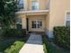 Townhome exterior featuring covered entry, manicured bushes, and well-maintained lawn at 6250 Maisie Rd, Zephyrhills, FL 33542