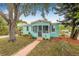 Charming turquoise home featuring a cozy screened porch, delightful landscaping, and inviting curb appeal at 653 E Spruce St, Tarpon Springs, FL 34689