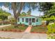 Charming turquoise home featuring a cozy screened porch, delightful landscaping, and inviting curb appeal at 653 E Spruce St, Tarpon Springs, FL 34689