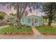 Charming turquoise home with a cozy front porch, mature landscaping, and a lush green lawn at 653 E Spruce St, Tarpon Springs, FL 34689