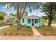 Charming turquoise home with a cozy front porch, mature landscaping, and a lush green lawn at 653 E Spruce St, Tarpon Springs, FL 34689