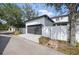 View of the detached garage featuring a gray door, white fence, and surrounding green foliage at 7307 S Trask St, Tampa, FL 33616